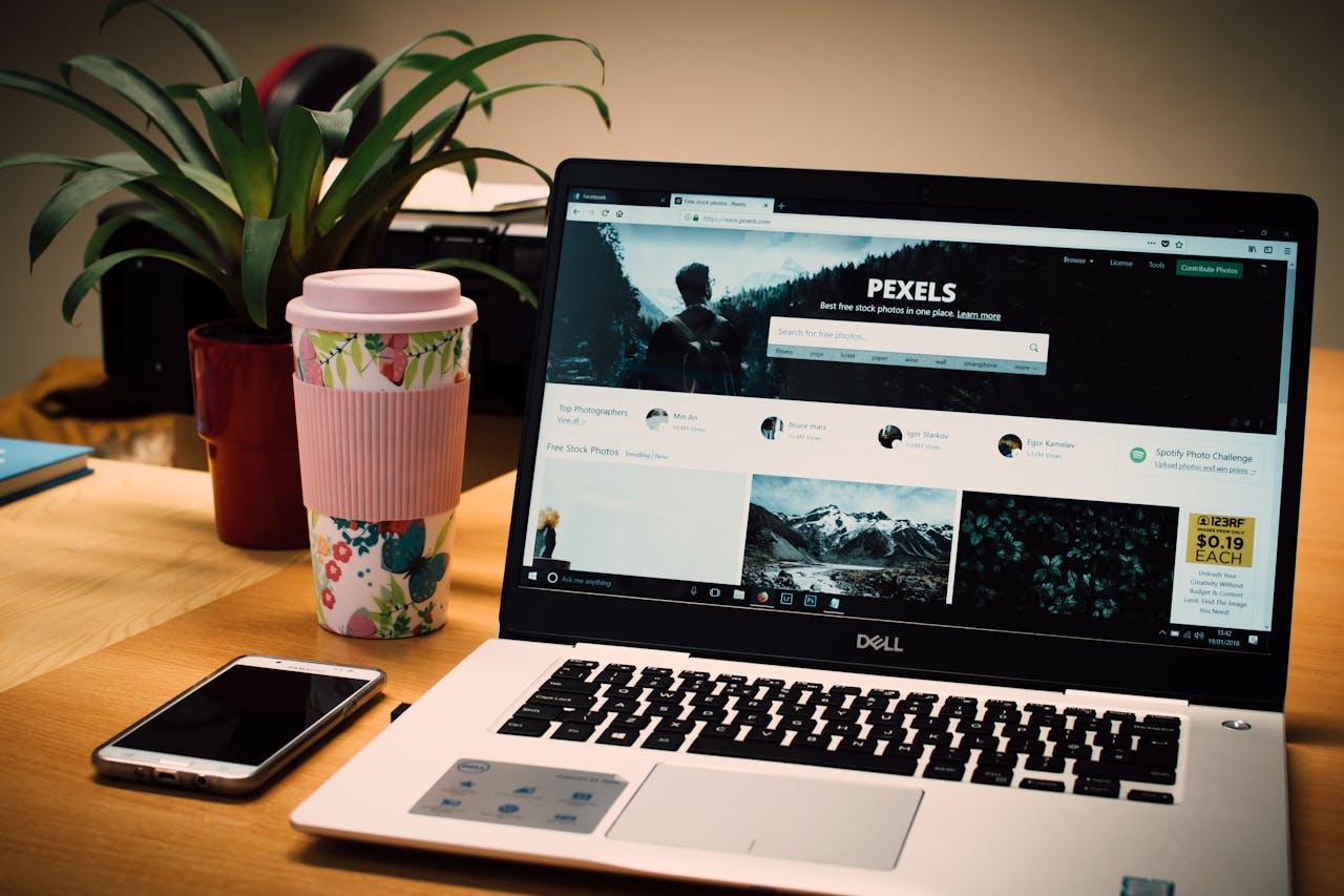 our-stories A tidy desk setting with a laptop showing a stock photo website and a smartphone.